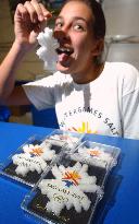 In preparation for the upcoming Winter Olympics, a young woman licks a souvenir made from salt taken from the Great Salt Lake adjacent to the hosting city.  The souvenir costs $9 each.